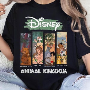 Op de afbeelding: Zwart T-shirt met een groen Disney-logo en een collage van personages uit Disney-films. De personages zijn Broeder Beer, Tarzan, Jungle Book en The Lion King. De tekst "Animal Kingdom" staat onder de collage.