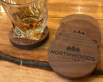 May include: Four round wooden coasters with a dark brown finish. The top coaster features the text "NORTHWOODS CUSTOM" with a small image of three pine trees.