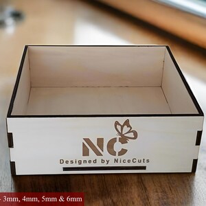 K&ouml;nnte beinhalten: Eine wei&szlig;e Holzkiste mit einem Schmetterlingsdesign und dem Text "NC Designed by NiceCuts". Die Box ist f&uuml;r den Laserschnitt geeignet und in den St&auml;rken 3 mm, 4 mm, 5 mm und 6 mm erh&auml;ltlich.