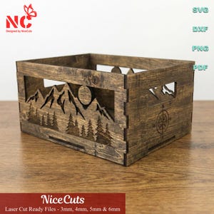 Op de afbeelding: Een gebeitste houten kist met berg- en bosuitsparingen. De kist heeft een kompasontwerp en de tekst "Nice Cuts". De kist is ontworpen voor lasersnijbestanden en is verkrijgbaar in diktes van 3 mm, 4 mm, 5 mm en 6 mm.
