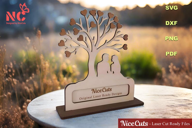 Puede incluir: Un recorte de madera de un &aacute;rbol con corazones como hojas y dos figuras de pie debajo. El &aacute;rbol est&aacute; sobre una base con el texto "Nice Cuts Original Laser Ready Designs".