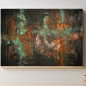 May include: Abstract textured painting with a dark background, featuring strokes of orange, teal, and gray. The artwork is framed in a light wood. The painting is displayed above a wooden table with pottery.
