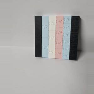 May include: A set of rectangular plastic shims arranged in a grid. The columns are colored black, light blue, white, pink, light blue, and black. Each shim is embossed with a fraction: 1/2, 1/3, 1/4, 1/6, or 1/8, indicating its specific thickness.