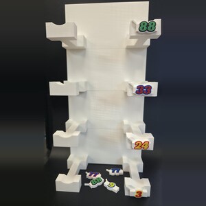 May include: A white vertical display stand with four levels of horizontal supports featuring U-shaped cradles. The right side displays the numbers 88, 33, and 24. Loose number pieces 77, 88, 9, and 3 are positioned at the base of the white structure.