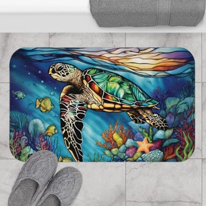 Könnte beinhalten: Eine farbenfrohe Badezimmermatte im Stil von Buntglas mit einer Meeresschildkröte, die durch ein Korallenriff schwimmt. Die Schildkröte ist grün, blau und orange mit einer gelben Schale. Das Korallenriff ist rot, orange und lila. In der rechten unteren Ecke befindet sich ein Seestern.