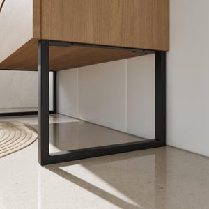 Peut inclure: Un pied de meuble rectangulaire en métal noir soutenant une armoire en bois clair. La structure présente un design en forme de U avec des plaques de fixation visibles fixées sous la surface en bois.