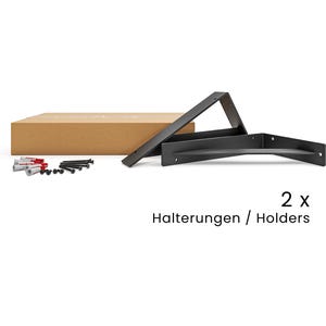 May include: Two black metal shelf brackets with screws in a brown cardboard box. The text "2x Halterungen / Holders" is printed below the brackets.