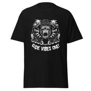 Puede incluir: Camiseta negra con un gráfico blanco de un gorila con gafas de sol y gorro, sosteniendo patines. El texto "GLIDE VIBES ONLY" está impreso debajo. La camiseta está hecha de un material suave.