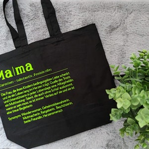 Einkaufstasche mit der Definition Mama für Caroline in Schwarz mit hellgrüner Aufschrift.