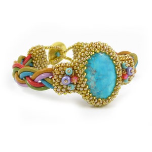 May include: A turquoise gemstone bracelet with a braided leather band and gold beads. The bracelet is decorated with small turquoise, purple, and red beads.