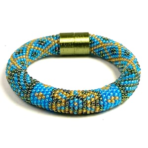 May include: A blue, gold and green beaded bracelet with a magnetic clasp.