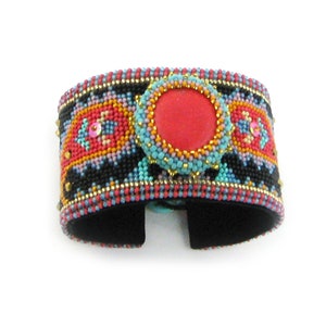 May include: A beaded cuff bracelet with a colorful geometric pattern and a large red cabochon stone in the center.