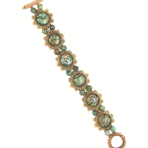 Può includere: Un braccialetto di perline verdi e dorate con un motivo floreale. Il braccialetto è realizzato con piccole perline rotonde e presenta una chiusura.