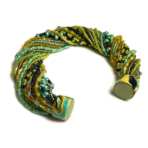 May include: A multi-strand beaded bracelet with green, gold, and black beads. The bracelet is made with a twisted design and has two decorative end caps.