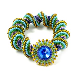 Könnte beinhalten: Ein Armband aus Perlen mit einem Spiraldesign in Grün-, Blau-, Lila- und Goldtönen. Das Armband hat einen großen blauen Edelstein in der Mitte.