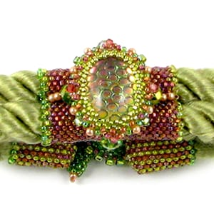 Pode incluir: Um bracelete de contas verdes e marrons com uma grande gema verde iridescente no centro.