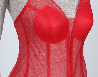 May include: Red mesh corset with a sweetheart neckline and boning. The corset is made of a sheer fabric with a red lining.