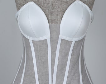 May include: White strapless corset with a mesh bodice and satin cups. The corset has a boned structure and a fitted silhouette.