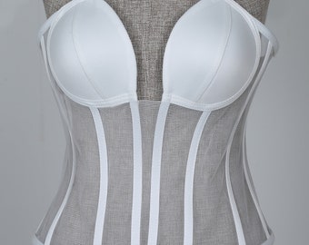 May include: White strapless corset with a mesh bodice and a satin cup. The corset has a boned structure and a v-shaped neckline.