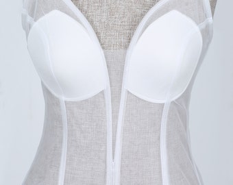 May include: White mesh corset with a sweetheart neckline and boning. The corset is made of a sheer fabric and has a fitted silhouette.