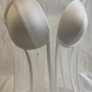 May include: White strapless bra with a mesh design. The bra has a hook and eye closure in the back.
