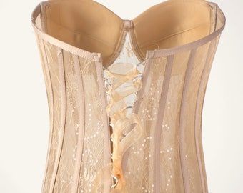 May include: A beige lace corset with a satin ribbon tied at the back. The corset has a boned structure and is designed to cinch the waist.
