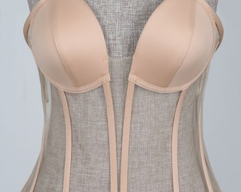 May include: A nude-colored mesh corset with a satin bust. The corset has a V-shaped neckline and a boned structure.