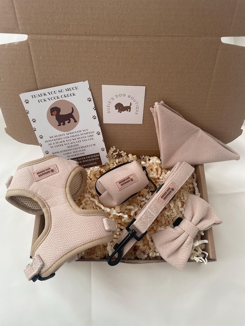 Puede incluir: Un conjunto de arn&eacute;s para perro en color beige con patr&oacute;n de espiga, que incluye arn&eacute;s, correa, pajarita, dispensador de bolsas y pa&ntilde;uelo triangular. Incluye una tarjeta de agradecimiento y una tarjeta con el logo de Suzie's Dog Boutique.