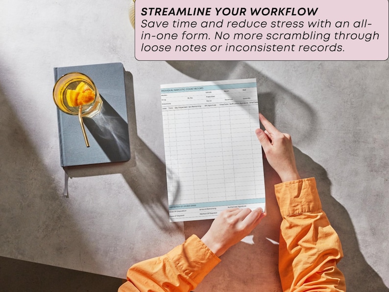 May include: A person holding a form with a grid layout, with the text "STREAMLINE YOUR WORKFLOW". A glass with a drink and a straw sits on a gray notebook. The person wears an orange long-sleeved shirt.