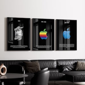 Puede incluir: Tres carteles enmarcados en negro con texto blanco y diferentes diseños de logo de Apple. El primer cartel presenta una ilustración en blanco y negro de una manzana con una cinta alrededor. El segundo cartel presenta un logo de manzana de colores arcoíris. El tercer cartel presenta un logo de manzana azul.