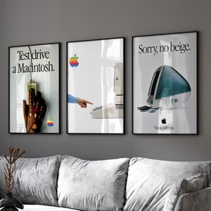 Può includere: Tre poster incorniciati su una parete grigia sopra un divano grigio e una sedia marrone. I poster sono per il computer Apple Macintosh. Il testo sui poster recita "Test drive a Macintosh." "Sorry, no beige." e "Think different."