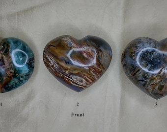 May include: Three heart-shaped stones with unique patterns and colors. The stones are numbered 1, 2, and 3. Stone 1 has blue, green, and purple hues. Stone 2 has brown, tan, and blue tones. Stone 3 has gray, blue, and brown colors.