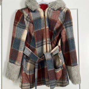 May include: A vintage plaid coat with a hood and faux fur trim. The coat features a brown zipper, a matching belt, and faux fur cuffs. The plaid pattern includes shades of red, blue, and cream.