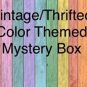 May include: Image of a wooden background with vertical planks painted in various pastel colors. The text "Vintage/Thrifted Color Themed Mystery Box" is overlaid in black, indicating a curated collection.