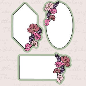 May include: Three floral-themed cookie cutters in different shapes: a hexagon, an oval, and a rectangle. Each cutter features a white interior and is outlined in green. The cutters are decorated with pink and purple flowers.
