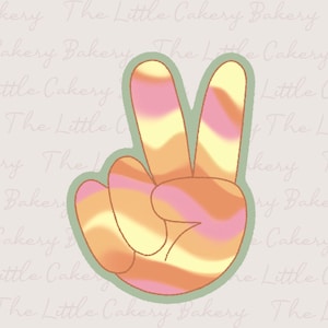 May include: A peace sign cookie cutter with a light green outline. The interior features a swirled design of orange, yellow, and pink hues, creating a retro, groovy aesthetic. Ideal for baking themed treats.