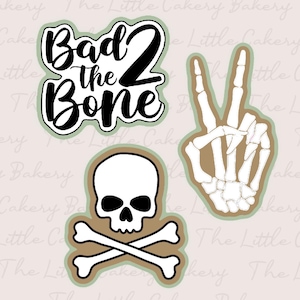 May include: Three cookie cutters in the shape of a skull and crossbones, a peace sign with a skeleton hand, and a phrase that reads "Bad to the Bone".
