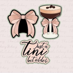 May include: Three cookie cutters, one shaped like a bow, one shaped like a glass with a bow on the stem, and one with the text "Just a  tini bit older".