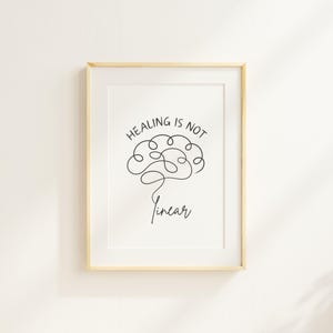 May include: A white framed print with a black line drawing of a brain with the text "Healing is not linear" in black.