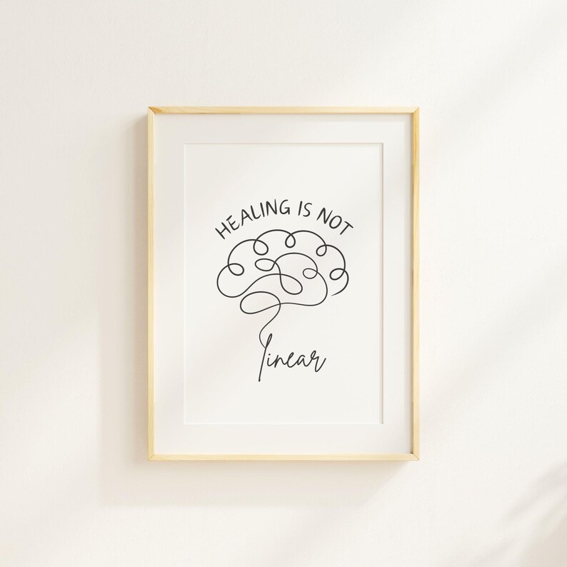 May include: A white framed print with a black line drawing of a brain with the text "Healing is not linear" in black.