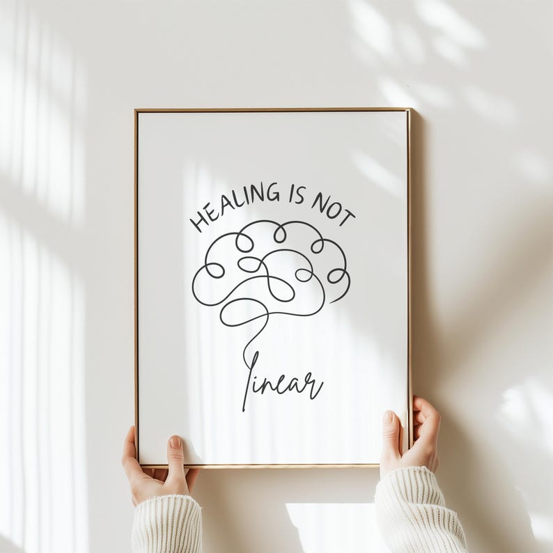 May include: A framed print with a white background and black text that reads "Healing is not linear". A stylized brain is drawn in black line art above the text.