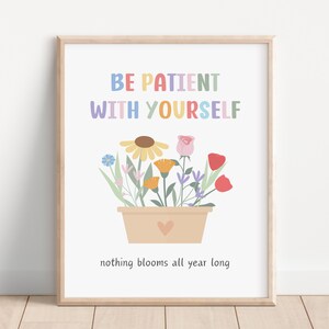 Puede incluir: Una impresión de arte de pared imprimible con una cita motivacional: "Sé paciente contigo mismo, nada florece todo el año." La cita está en colores arcoíris y está acompañada de un dibujo de una maceta de flores.
