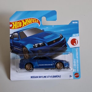 Può includere: Un'auto giocattolo pressofusa Hot Wheels Nissan Skyline GT-R (BNR34) blu nella sua confezione blister originale. La carta presenta uno sfondo blu con una grafica dell'auto, il logo Hot Wheels e il testo 199/250, 10/10 e 3+.