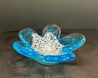 May include: A flower-shaped glass bowl in shades of blue. The centre of the bowl features white speckled detailing. The clear glass edges give a delicate appearance. A unique decorative item for the home.