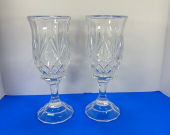 May include: Two clear glass candle holders with a diamond and fan pattern. The candle holders have a flared top, a pedestal base, and are approximately 8 inches tall.