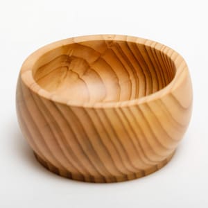 Può includere: Ciotola in legno artigianale di colore marrone chiaro. Ha una forma arrotondata con un'ampia apertura e una base visibile. La venatura del legno è visibile, aggiungendo consistenza. Adatta per servire o decorare.