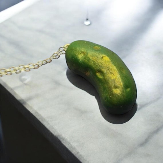 A tiny, absurdly detailed hand-sculpted polymer clay dill pickle you can actually wear — niche, weird, and delightfully committed to the bit.