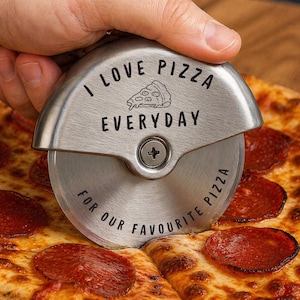 May include: A stainless steel pizza cutter with the words "I LOVE PIZZA EVERYDAY FOR OUR FAVORITE PIZZA" engraved on the handle. The cutter is slicing through a pizza topped with pepperoni.