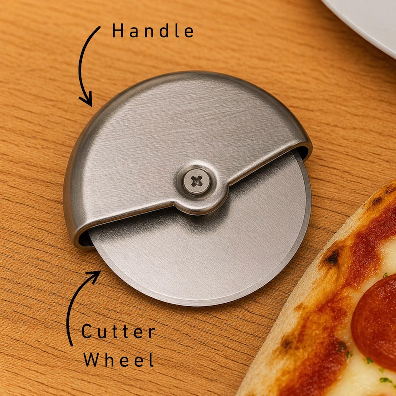 May include: A stainless steel pizza cutter with a circular blade and a curved handle. The cutter wheel is visible, along with a portion of a pizza with pepperoni.