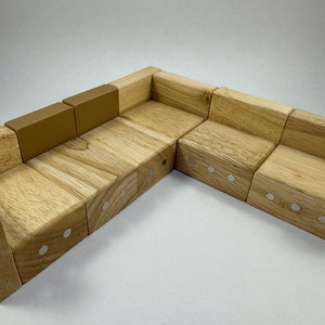 May include: A wooden sectional sofa made of multiple blocks with a light brown finish. The sofa has a light brown fabric cushion on the back and armrests. The sofa is made of wood blocks with silver metal accents.